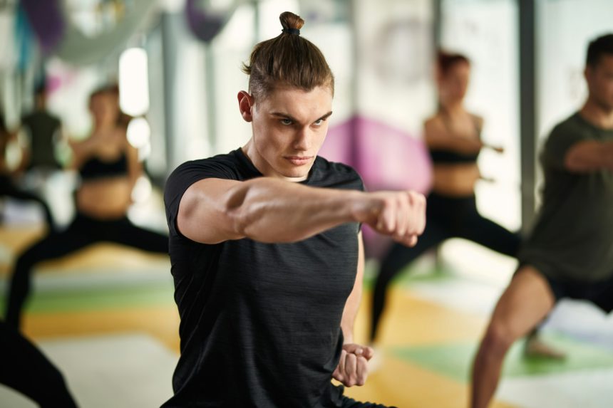 Dedicated athlete in fighting stance practicing martial arts at health cub.