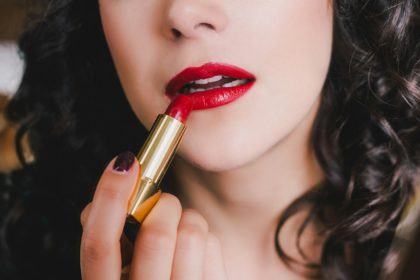 Woman applying red lipstick on lips. Bright makeup for special occasion